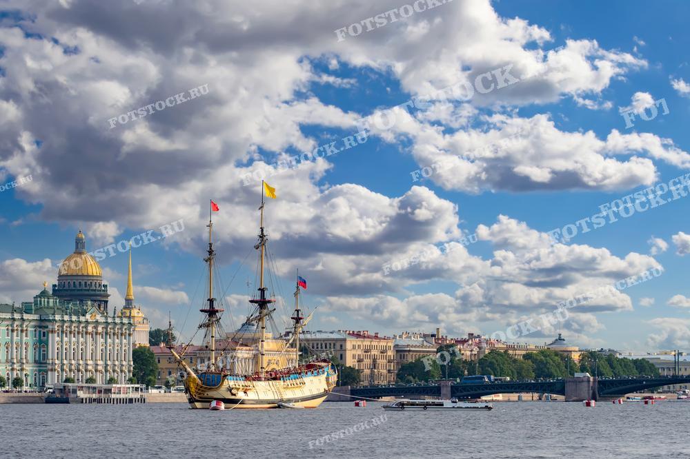 На фотографии представлен живописный вид на реку Неву в Санкт-Петербурге с парусником на переднем плане и Исаакиевским собором в качестве фона. Облака в небе добавляют динамику композиции. Этот снимок может быть использован для иллюстрации путеводителей по Санкт-Петербургу, образовательных статей о морской истории России, в туристических рекламных материалах или как красивый фон для рабочего стола.